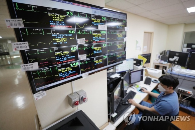 코로나19 생활치료센터 입소 환자 심박수를 살피는 의료진./사진제공=연합뉴스 